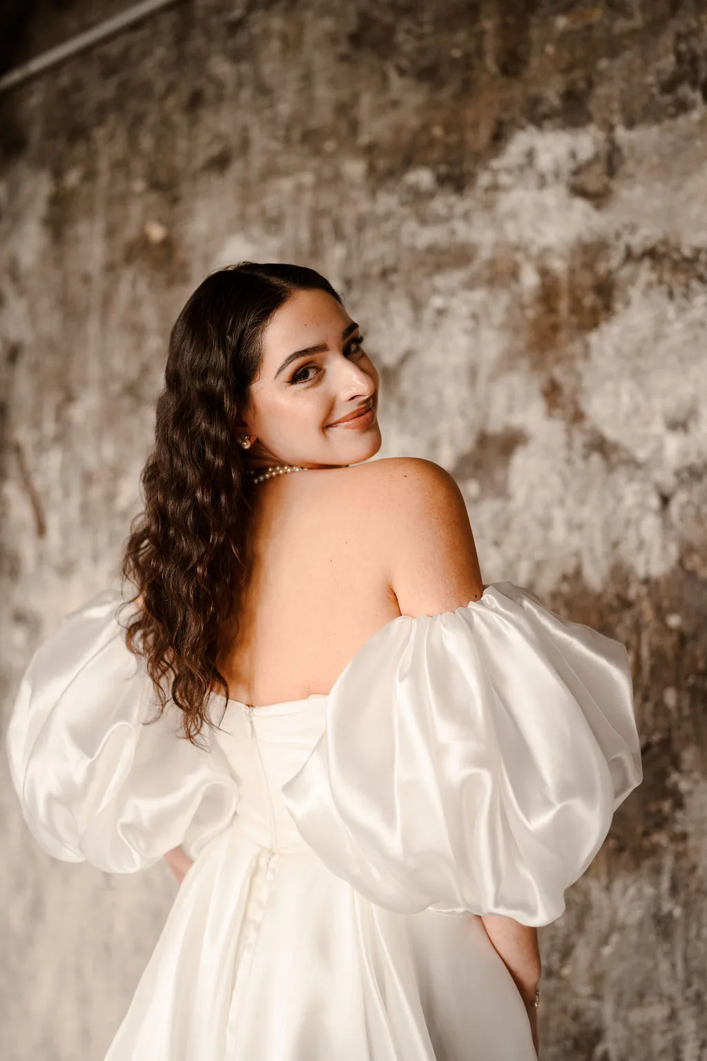 La mariée, de dos, regarde par-dessus son épaule
