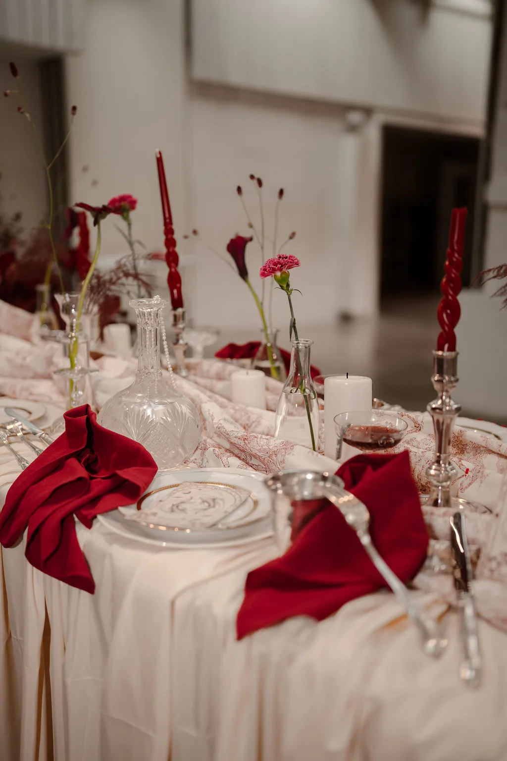 La table dressée, serviettes bordeaux et vaisselle dorée