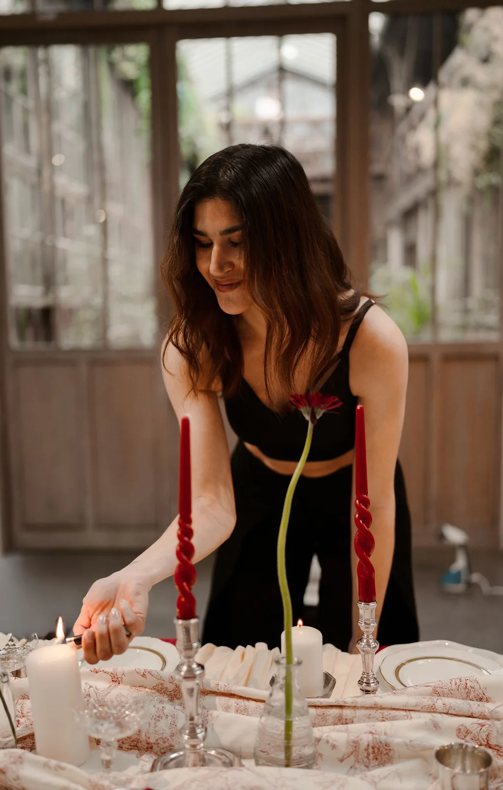 Sara allume les bougies d'une table de mariage sous une verrière